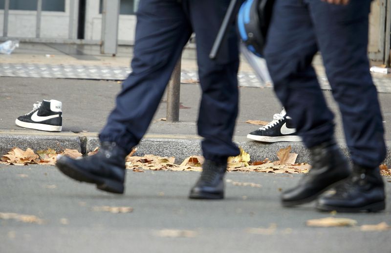 Police pass a pair of abandoned shoes seen left in the street near the Bataclan concert hall the morning after a series of deadly attacks in Paris