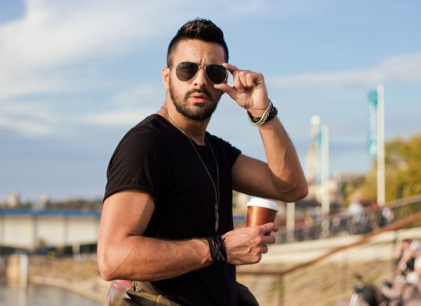 Handsome man outdoors drinking coffee. With sunglasses, a guy with beard. Instagram effect