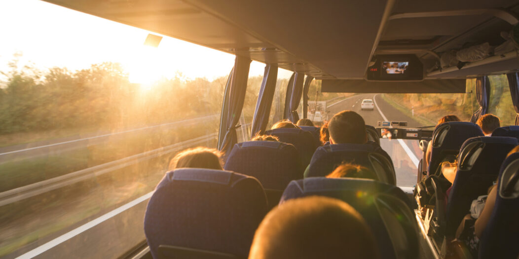 Background. Travel by bus. Bus interior. Salon of the bus with people fill the sun with light in the sunset. People travel on a big tourist bus. The bus rides along the mornings in the sunrise Background. Travel by bus. Bus interior. Salon of the bus with people fill the sun with light in the sunset. People travel on a big tourist bus. The bus rides along the mornings in the sunrise