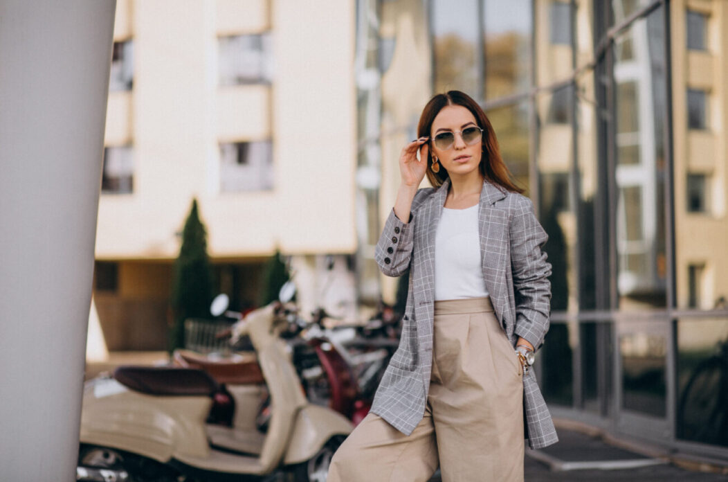 Young woman in suit standing by the scooter Young woman in suit standing by the scooter